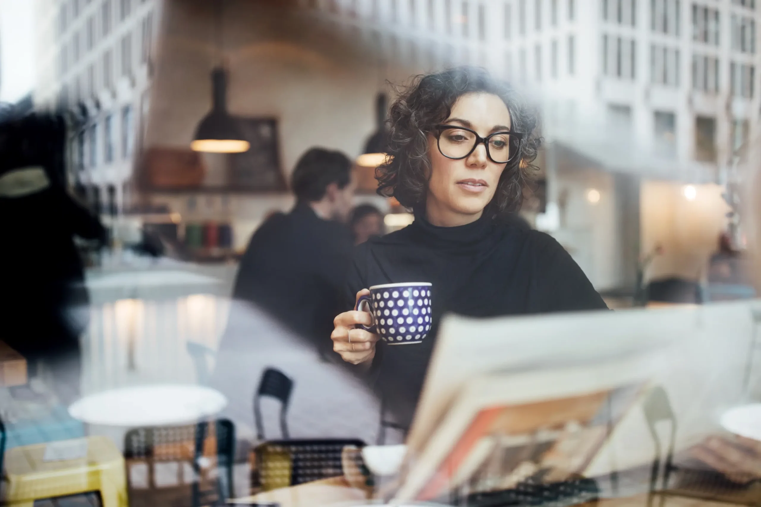 Donna d'affari di mezza età seduta in una caffetteria mentre legge un giornale.